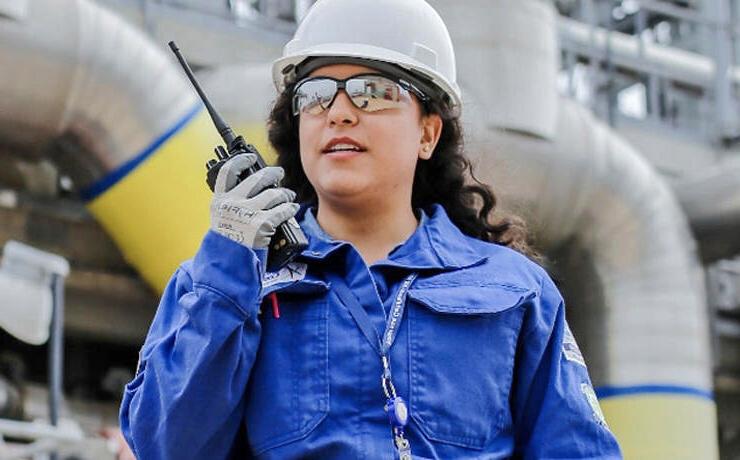 Woman wearing hard hat using a walkie-talkie.